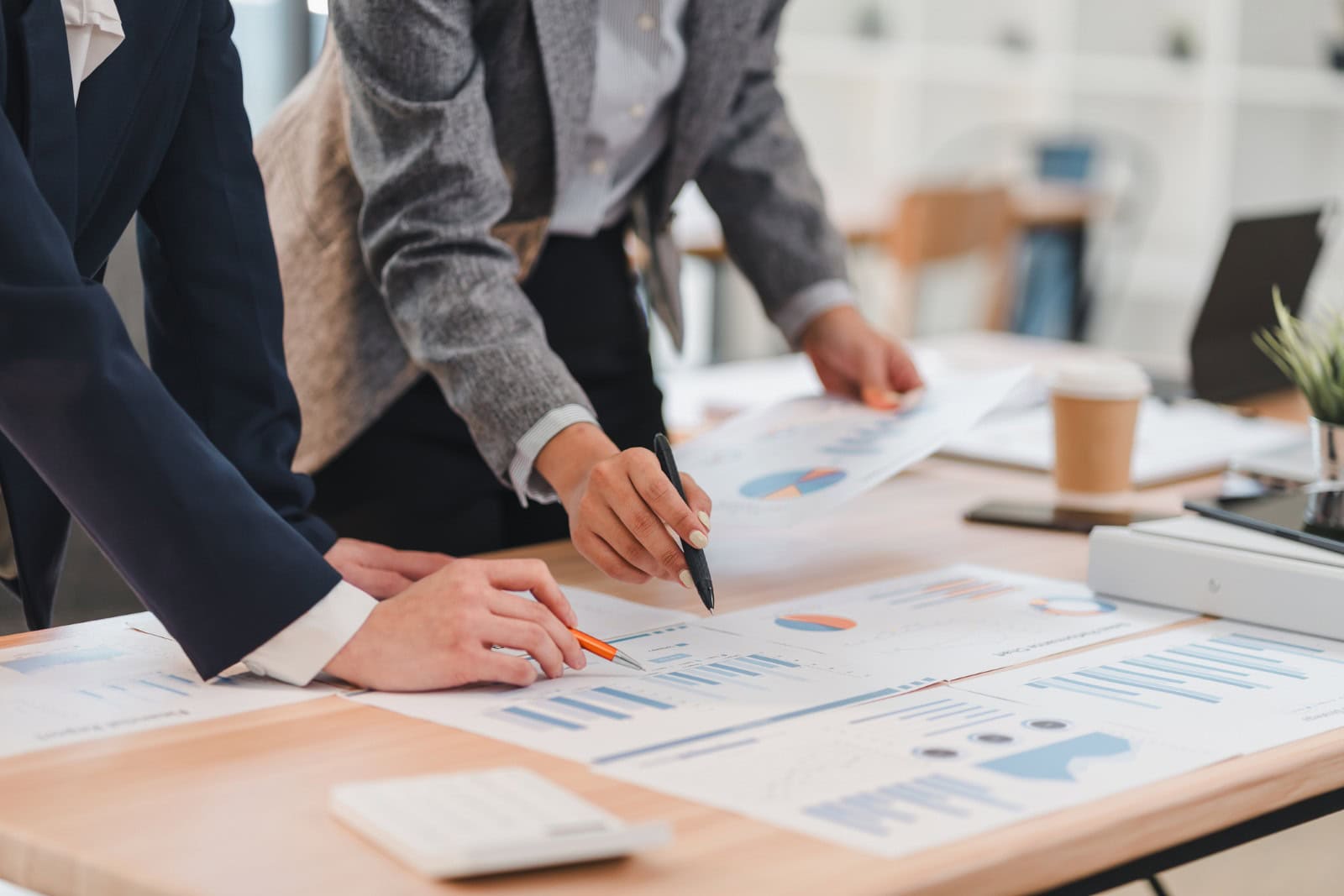 Man and woman standing at a desk reviewing charts and graphs