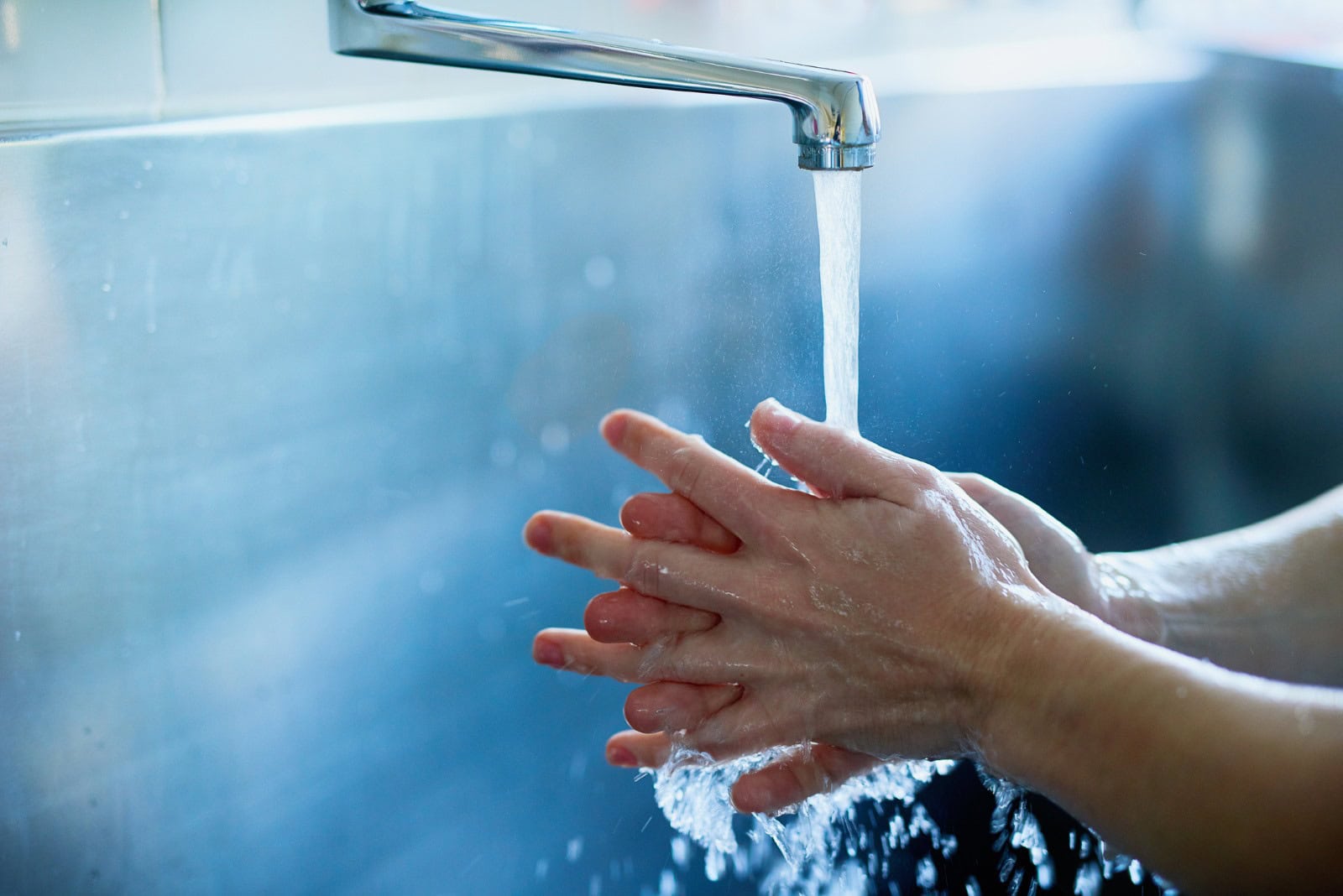 f66193a5-7721-4496-93c3-cdade2dc554e Man washing their hands under a large faucet