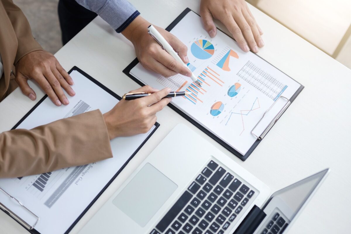 Confident,Business,Leader,,Business,Team,Meeting,Conference,In,Office,,The Man and woman standing over a desk reviewing charts and graphs