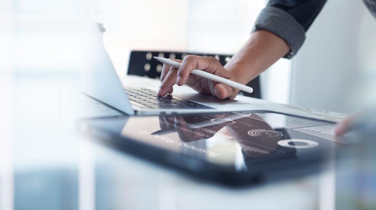 Businessman,Working,On,Laptop,,Using,Mobile,Phone,At,Modern,Office, Business person working on a laptop
