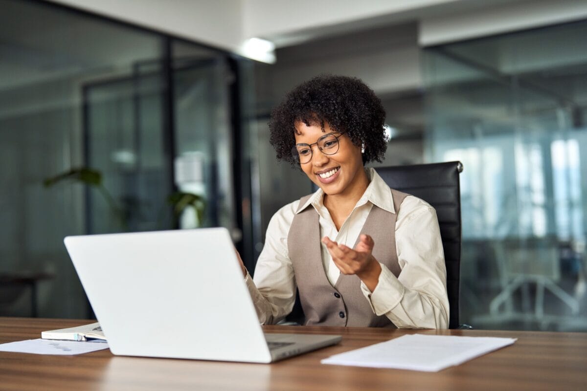 Happy,Professional,Young,African,Female,Hr,Manager,,Smiling,Business,Woman Professional young woman sitting at a desk and engaged in an online meeting